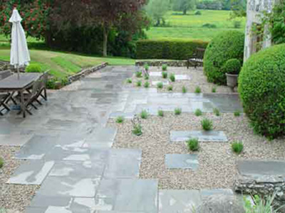 White of Witchampton - landscape gardener - A grey natural stone paving laid in a semi random pattern with gravel and planting.
